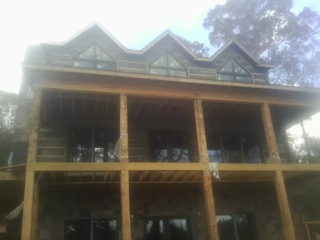 Dormers and porch framing on a large log home under construction — Roof Coating work by our crew in Emporia