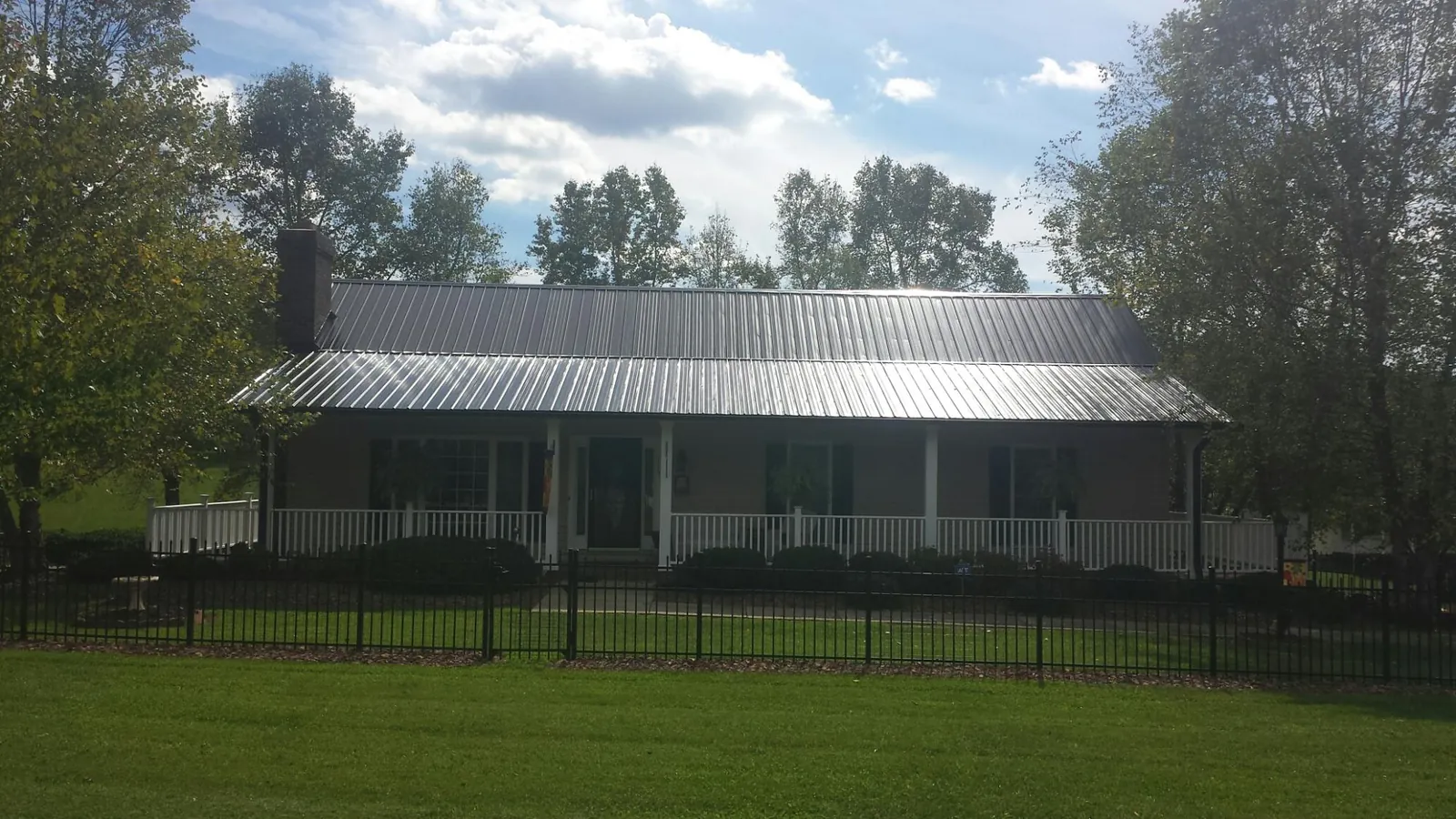 Gray metal roof on a brick ranch with a full width front porch — Gutter Guard Installation work by our crew in Emporia