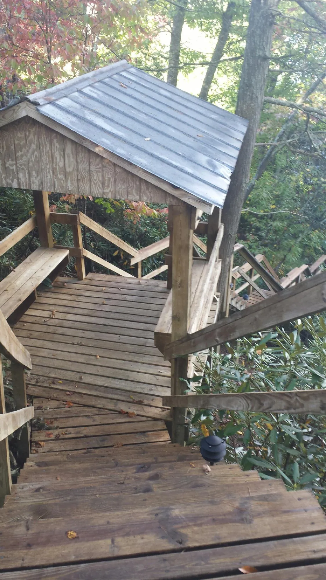 Metal roofed shelter over wooden steps on a wooded walkway — Skylight Repair & Installation work by our crew in Emporia